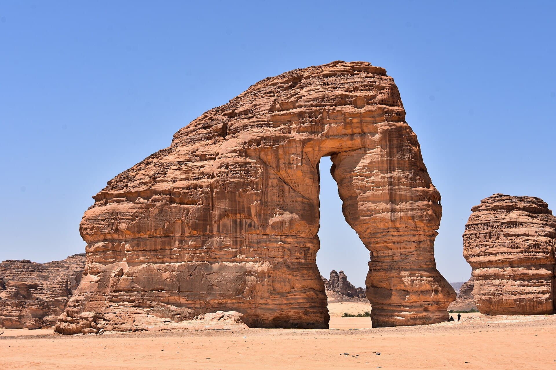 جبل الفيل في العلا، صخرة رملية ضخمة ذات قوس طبيعي يشبه خرطوم الفيل وسط الصحراء وتحت سماء زرقاء